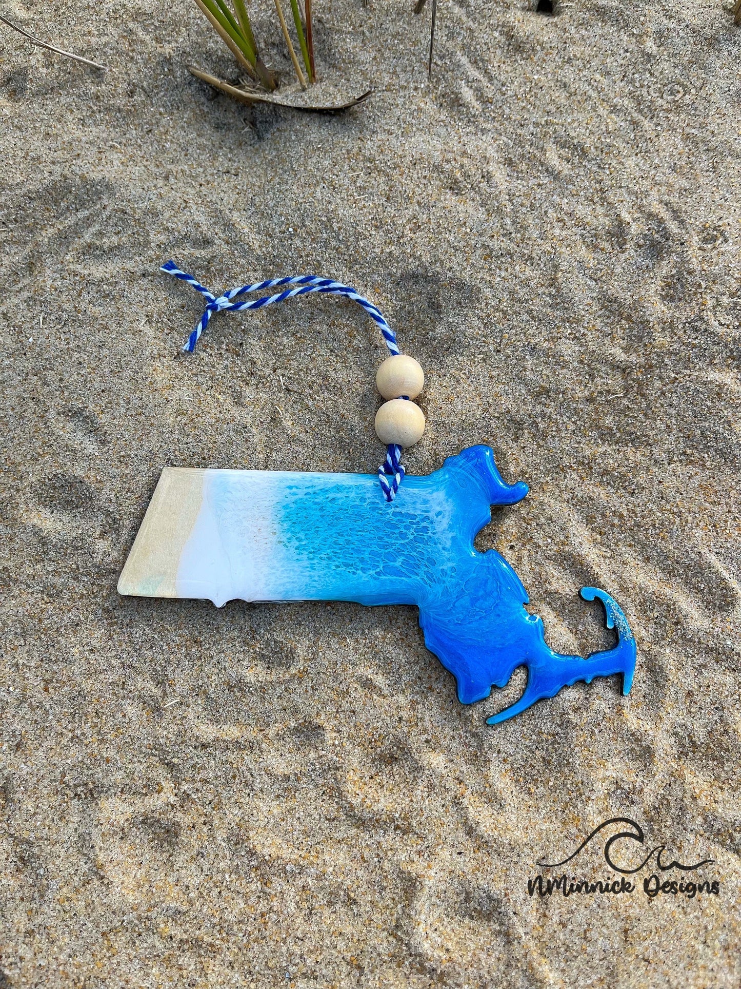 Massachusetts Beach Christmas Ornament laying against sand at the beach.