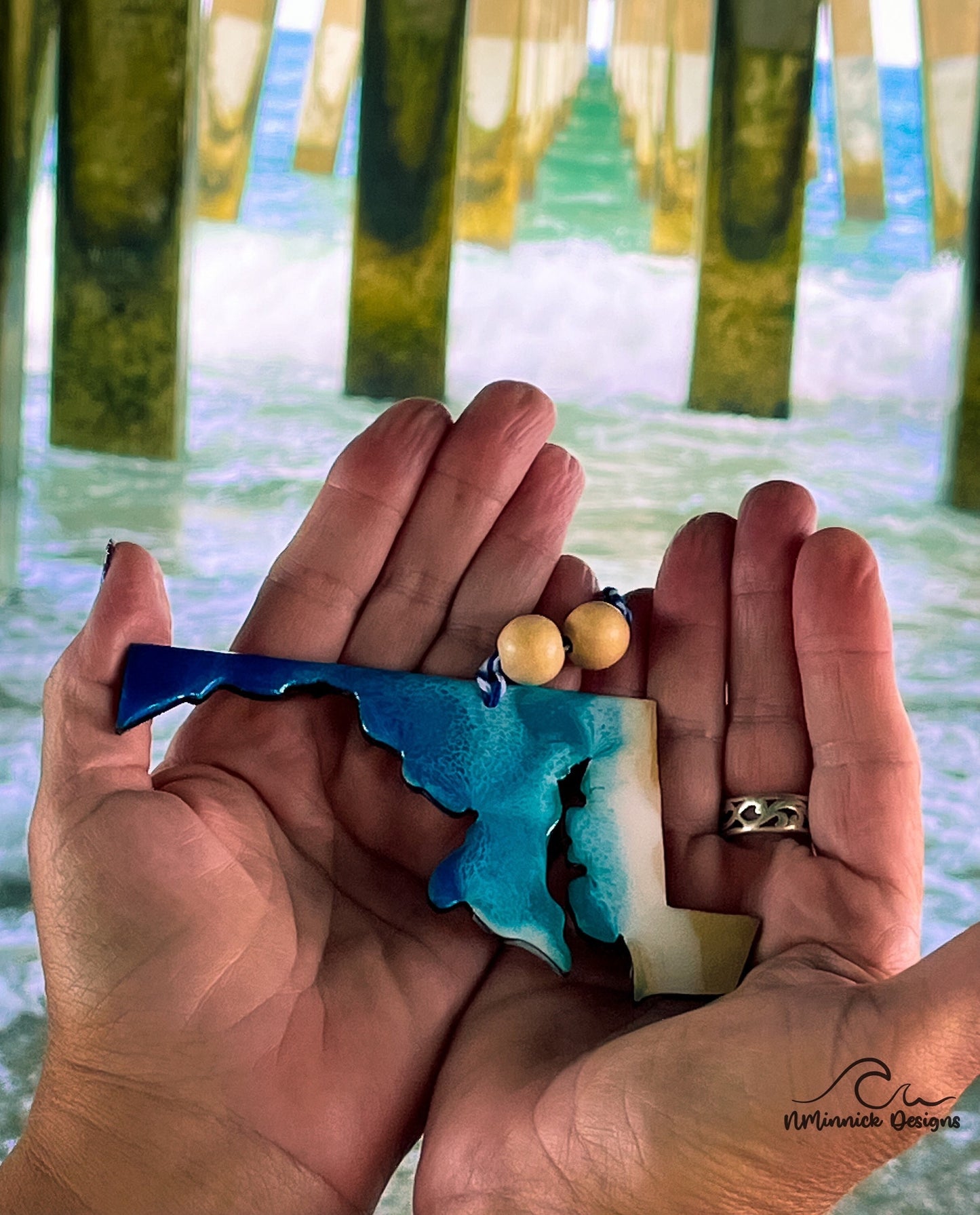 Maryland Beach Christmas Ornament in the palm of my hands underneath an ocean pier.
