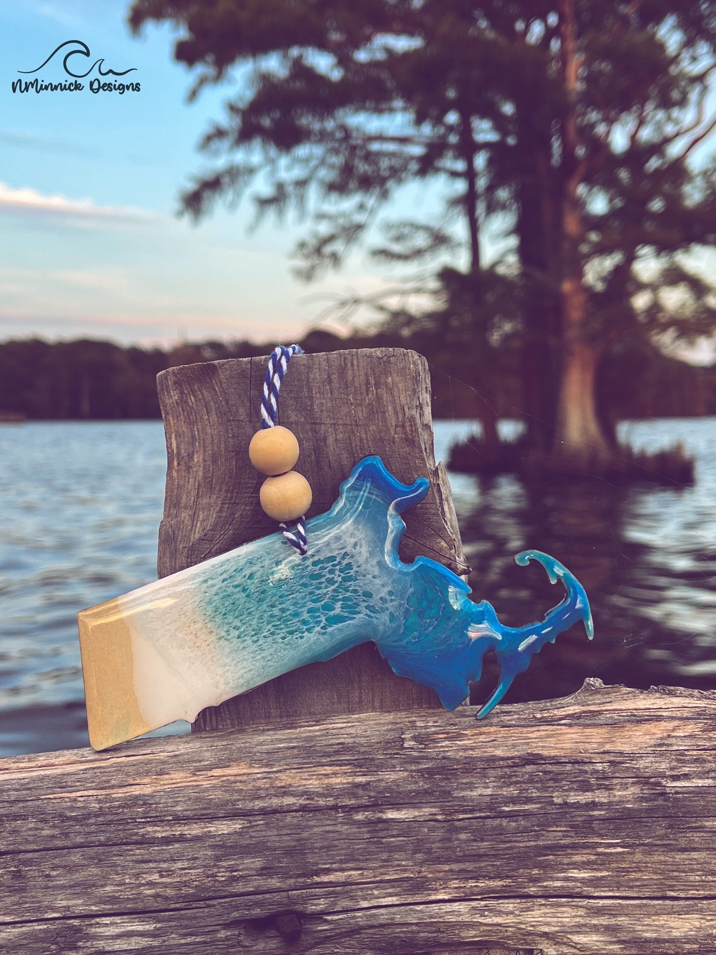 Massachusetts-shaped wooden Christmas ornament covered in blue and teal colored ocean resin art resembling the waves along Massachusetts' Atlantic Coast. Finished with blue and white baker's twine and two wooden beads.