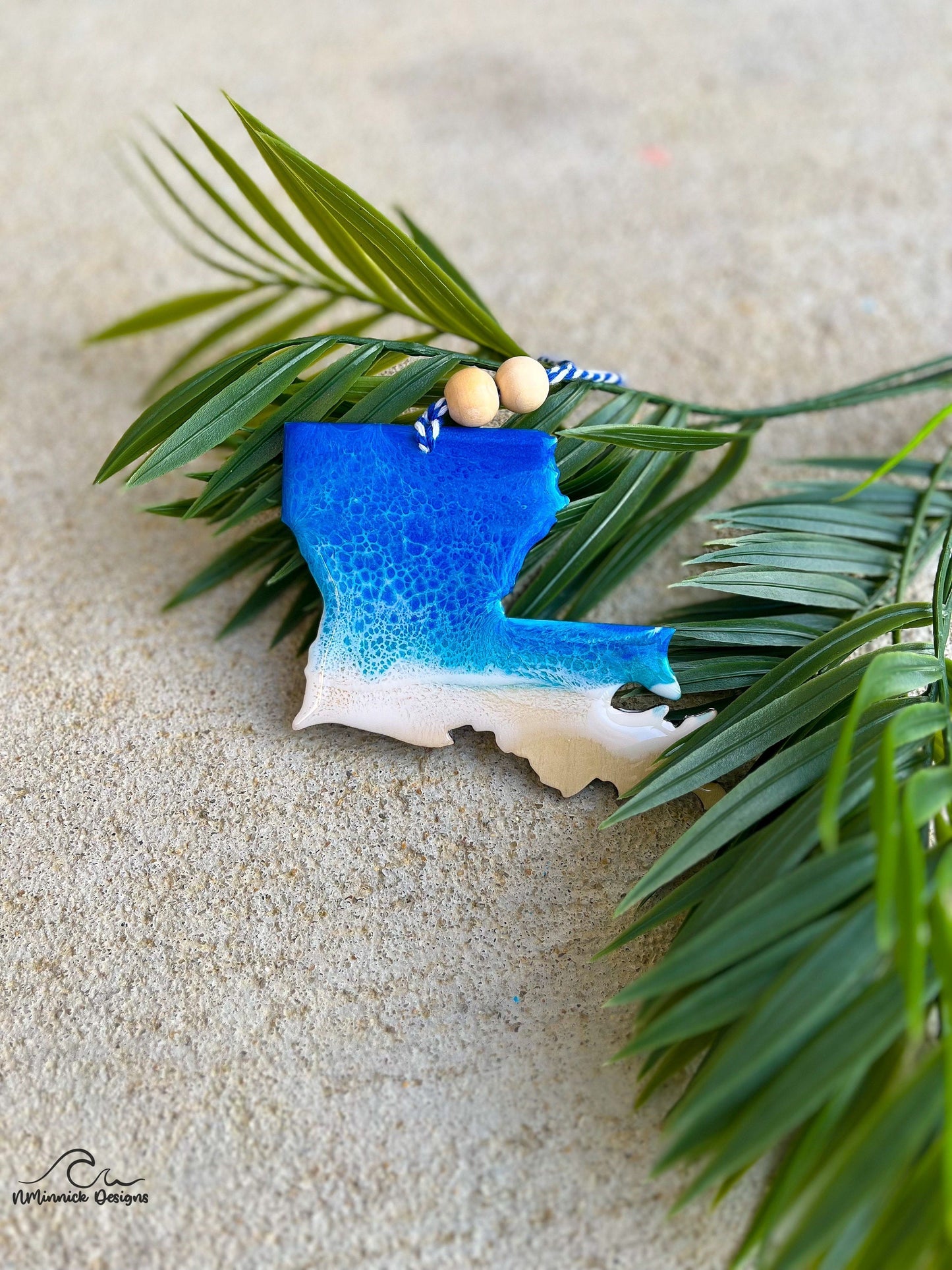 Louisiana beach ornament laying against palm leaves.