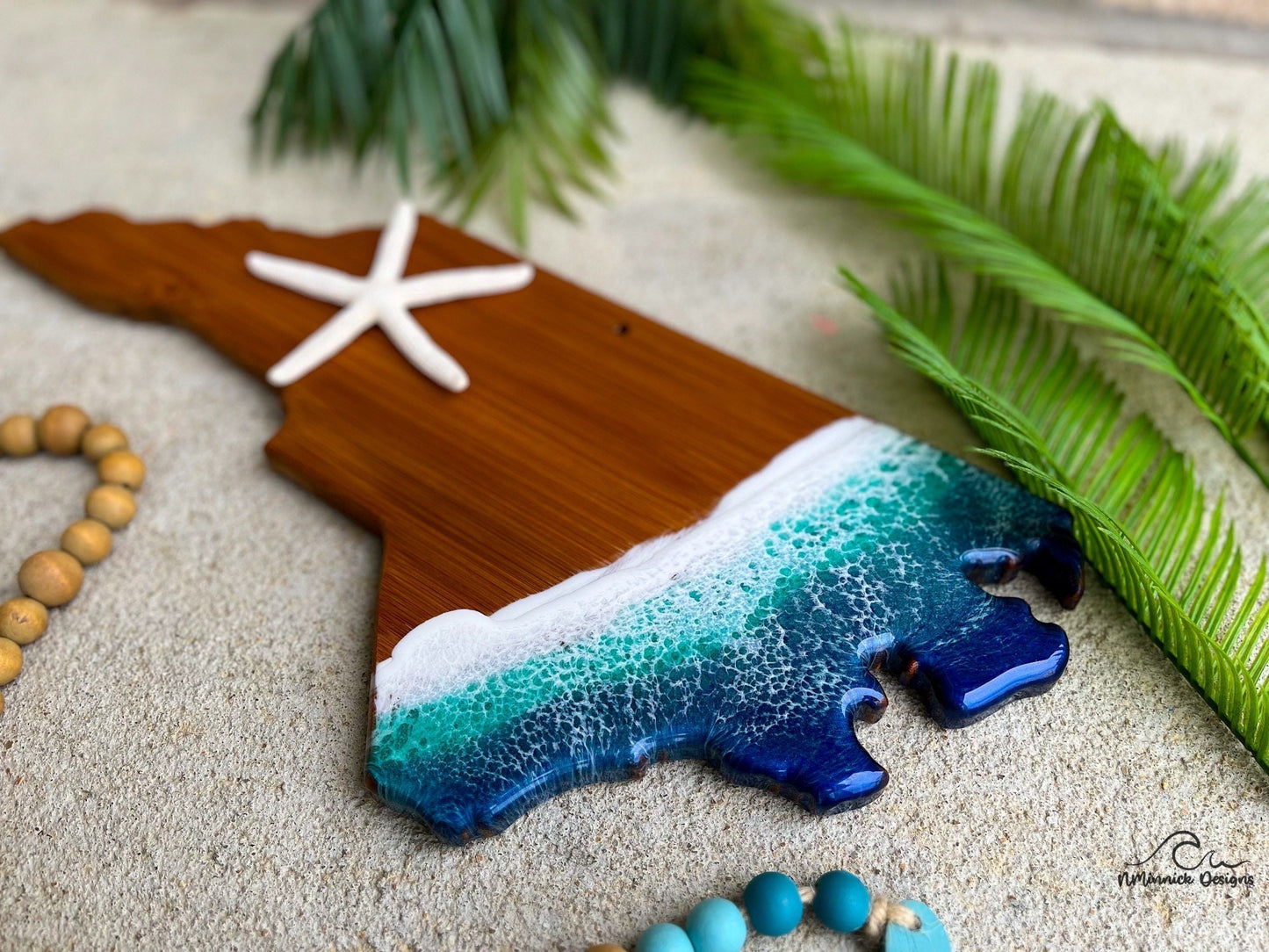 North Carolina bamboo charcuterie board with dark blue and teal ocean resin art on the coastline side of the board