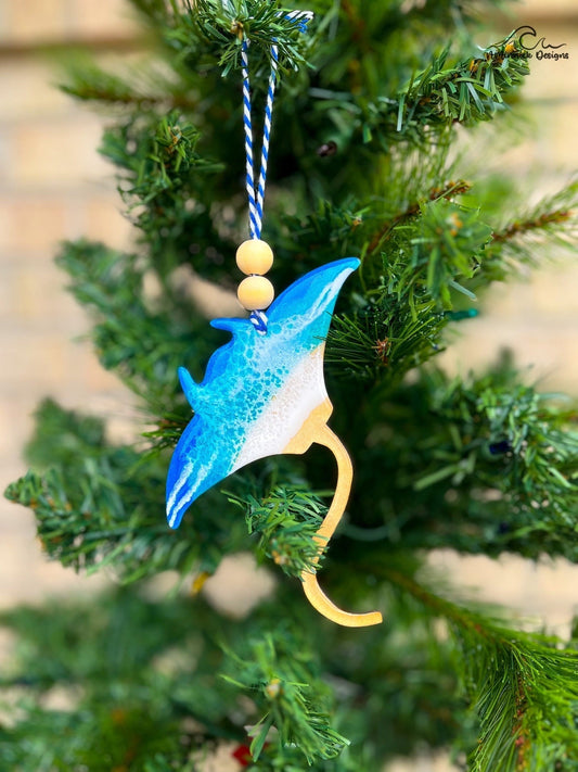 Manta Ray shaped wooden ornament with one side coated in blue ocean resin wave art and hanging on a christmas tree.