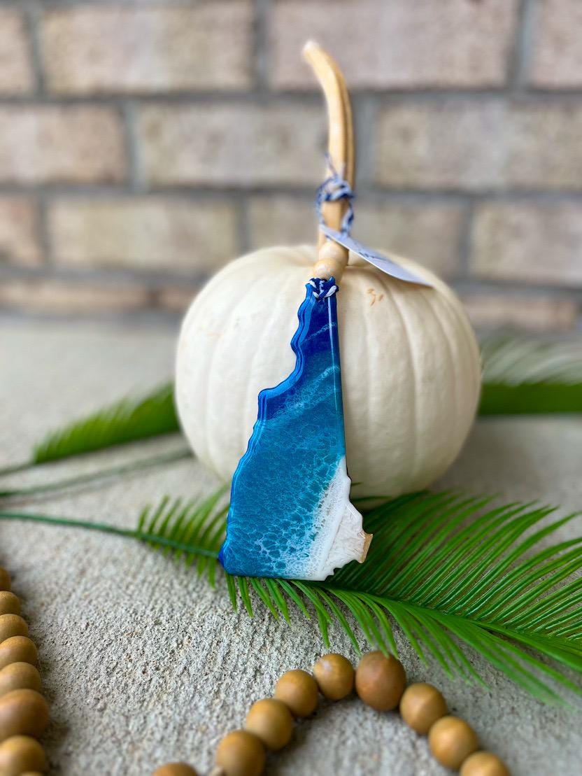 Handmade New Hampshire ocean resin ornament resting on a white pumpkin, coastal design inspired by New Hampshire beaches and ocean waves