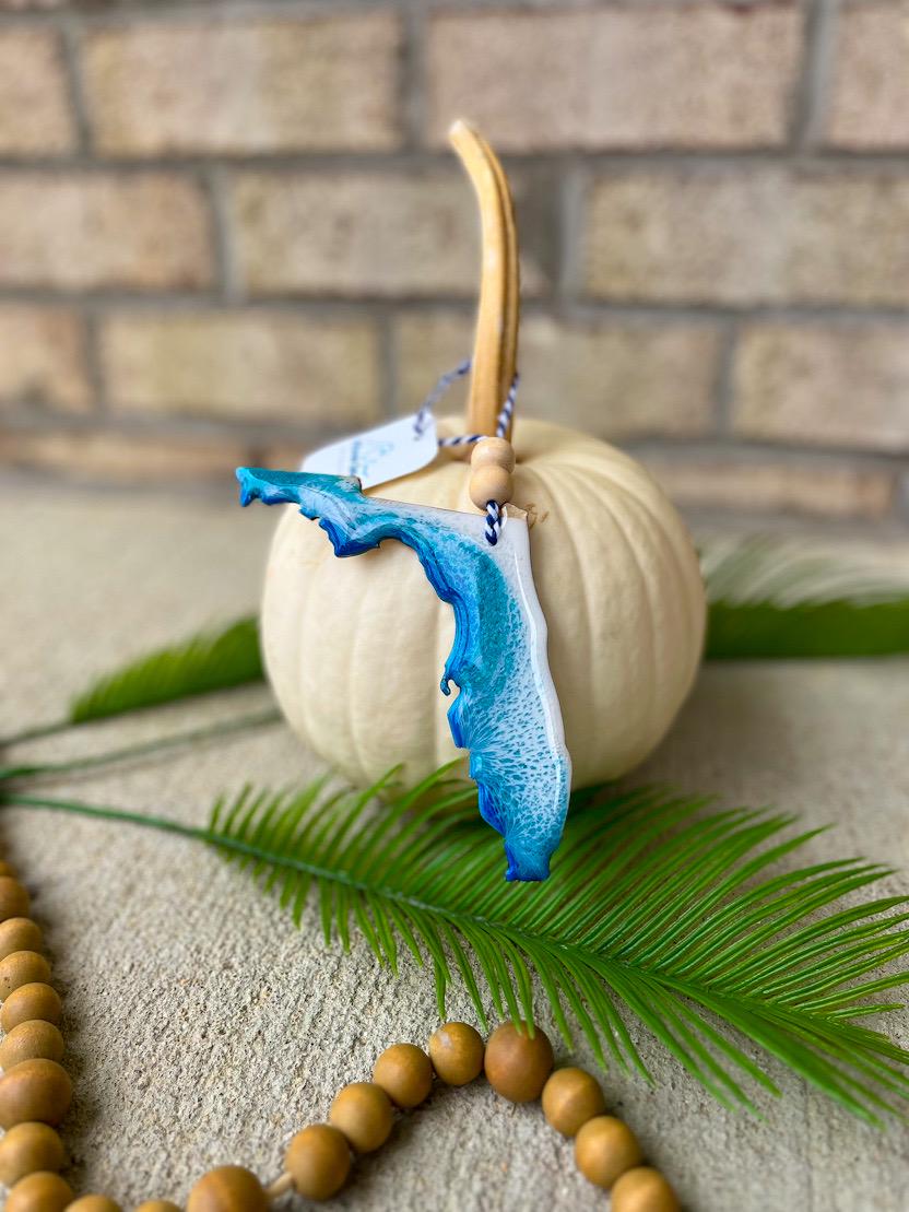 Handmade Florida Gulf Coast ocean resin ornament resting on a white pumpkin, coastal design inspired by Gulf beaches and ocean waves