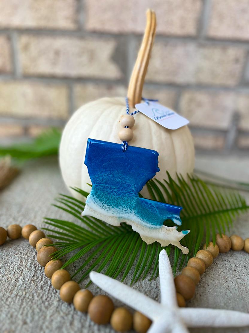 Handmade Louisiana state ocean resin ornament resting on a white pumpkin, coastal fall decor with ocean-inspired wave design