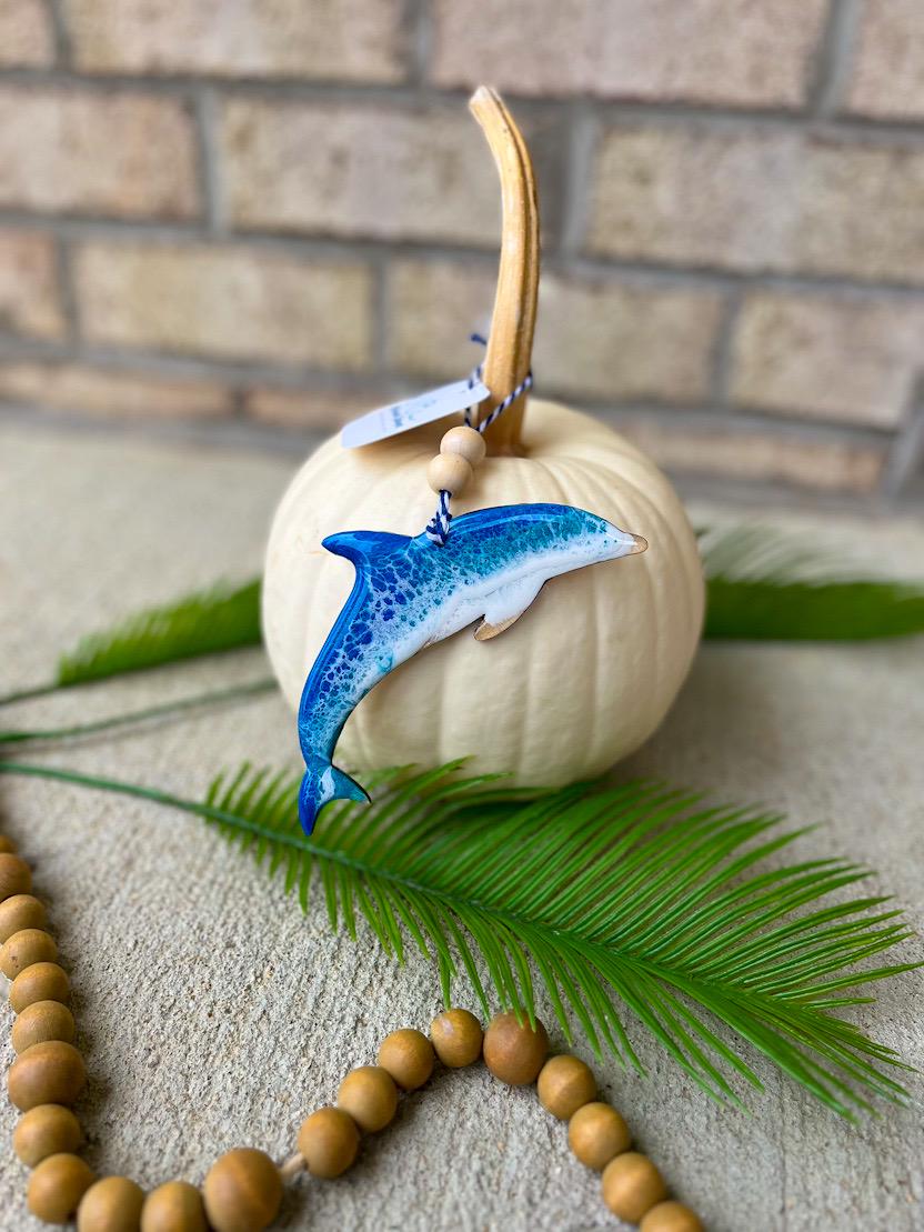 Handmade dolphin ocean resin ornament resting on a white pumpkin, coastal-inspired design with ocean wave details