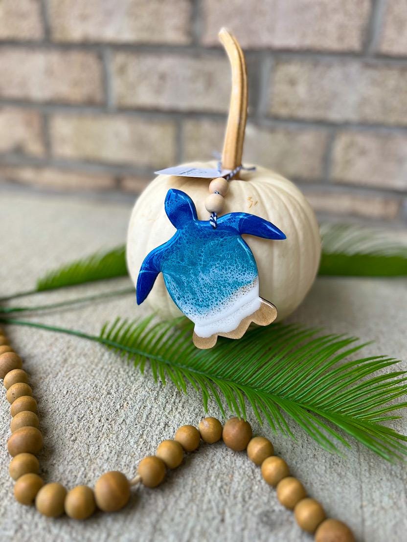Handmade sea turtle ocean resin ornament resting on a white pumpkin, coastal-inspired design with ocean wave details