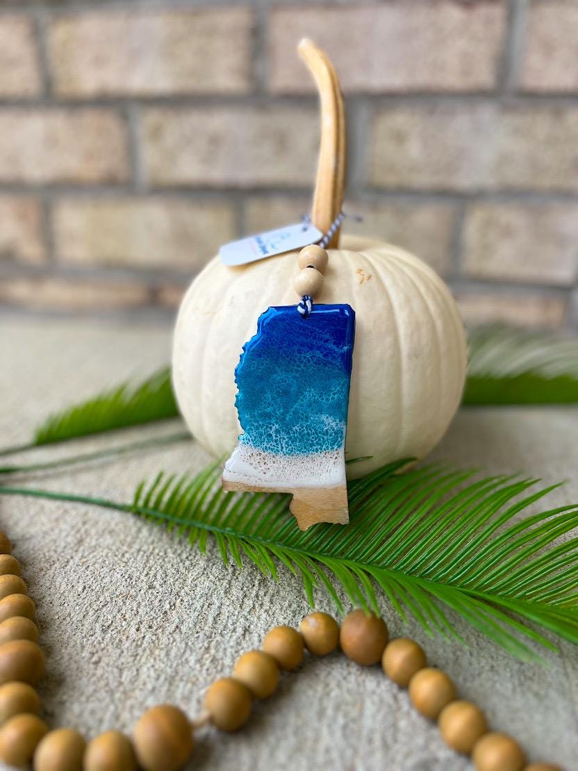 Coastal Mississippi ornament with ocean resin waves displayed on a white pumpkin, handcrafted beach-inspired decoration
