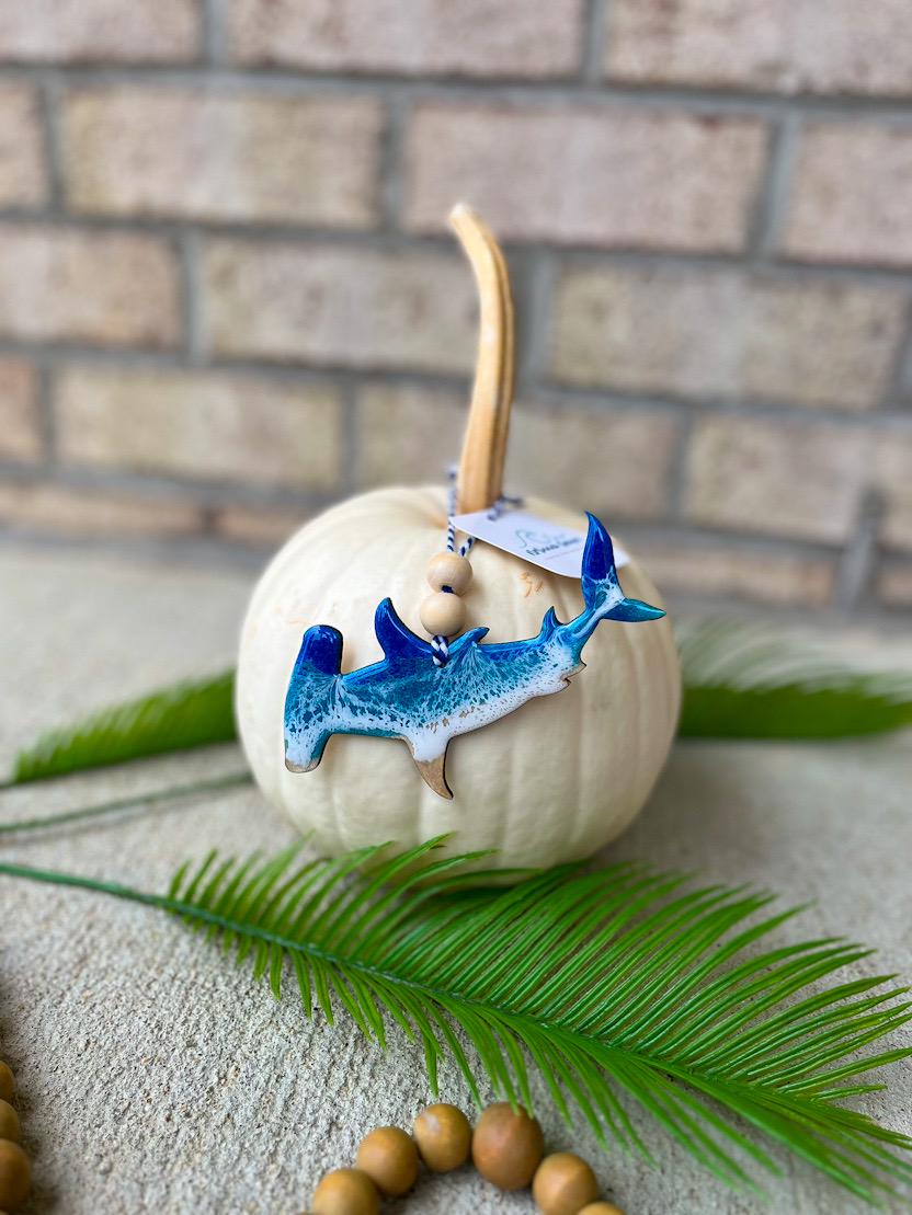 Handmade hammerhead shark ocean resin ornament resting on a white pumpkin, coastal beach-themed decor with ocean wave design