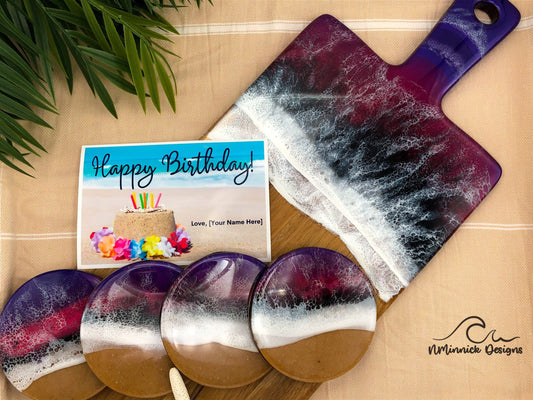 Long Acacia Wood Serving Board with Handle, top half covered in purple, red, and black ocean resin art resembling the waves of the ocean.  Matching set of 4 ocean resin art coated drink coasters with cork backings and a free Happy Birthday card.