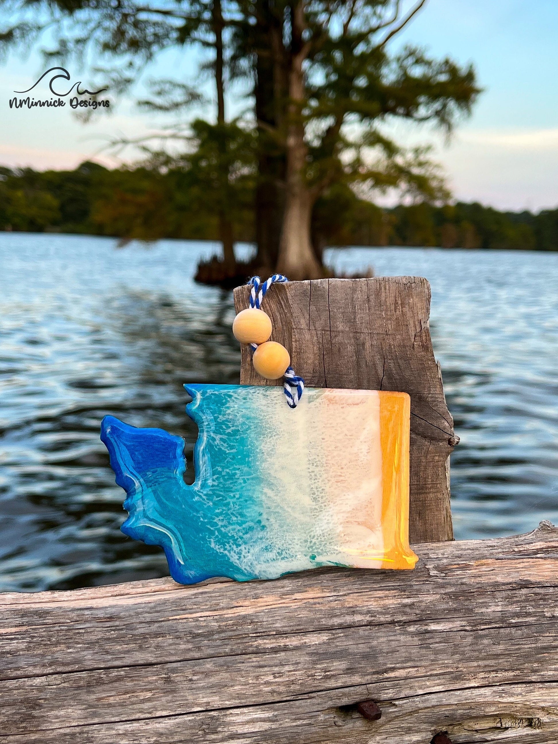 Washington State-shaped wooden Christmas ornament covered in blue and teal colored ocean resin art resembling the waves along Washington's Pacific Coast. Finished with blue and white baker's twine and two wooden beads.