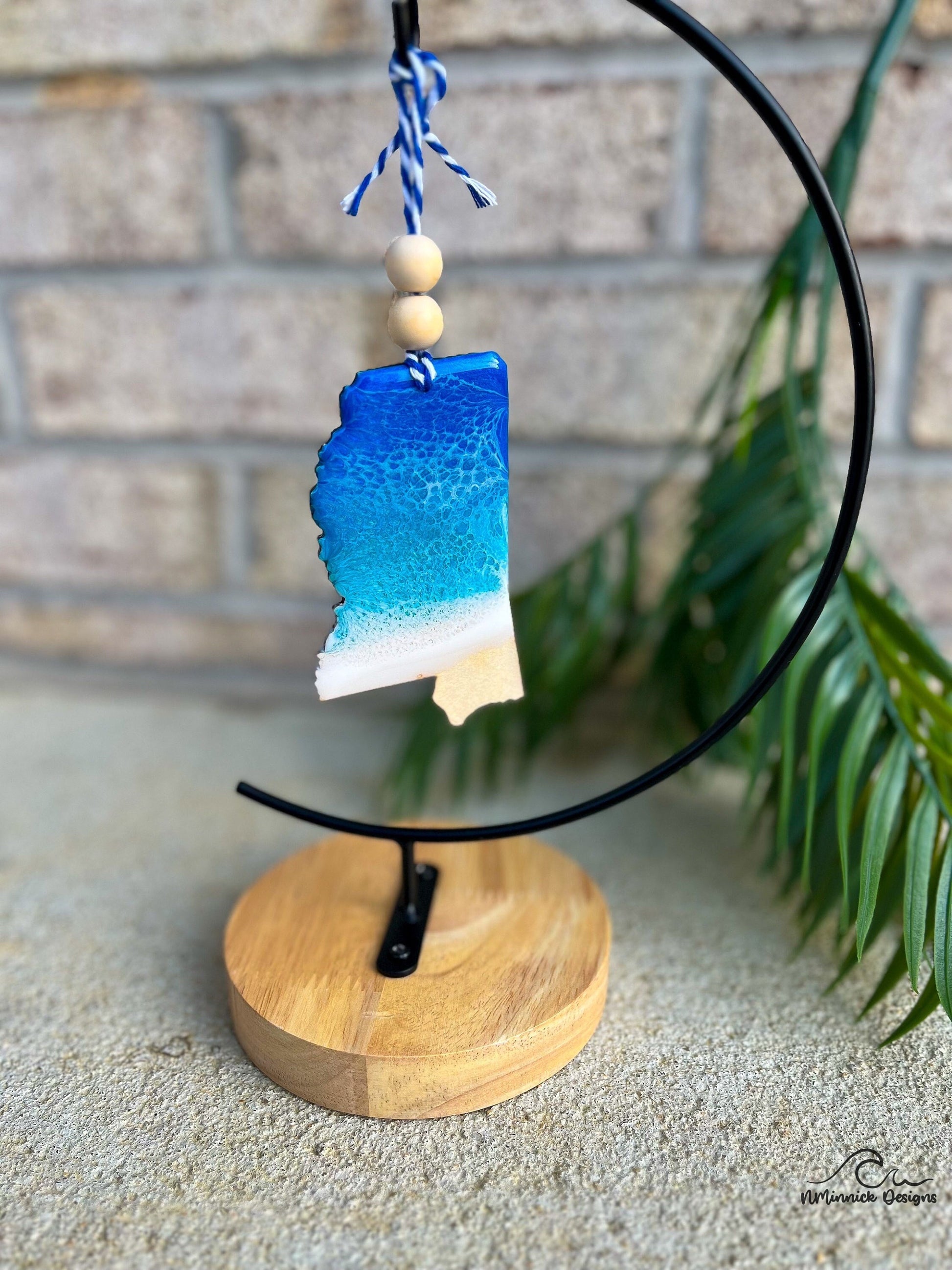 A Mississippi shaped wooden ornament with blue and white ocean resin art.