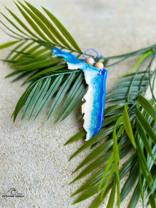 A florida shaped wooden ornament with blue and white ocean resin art. Finished with two wooden beads and a stand of bakers twine.