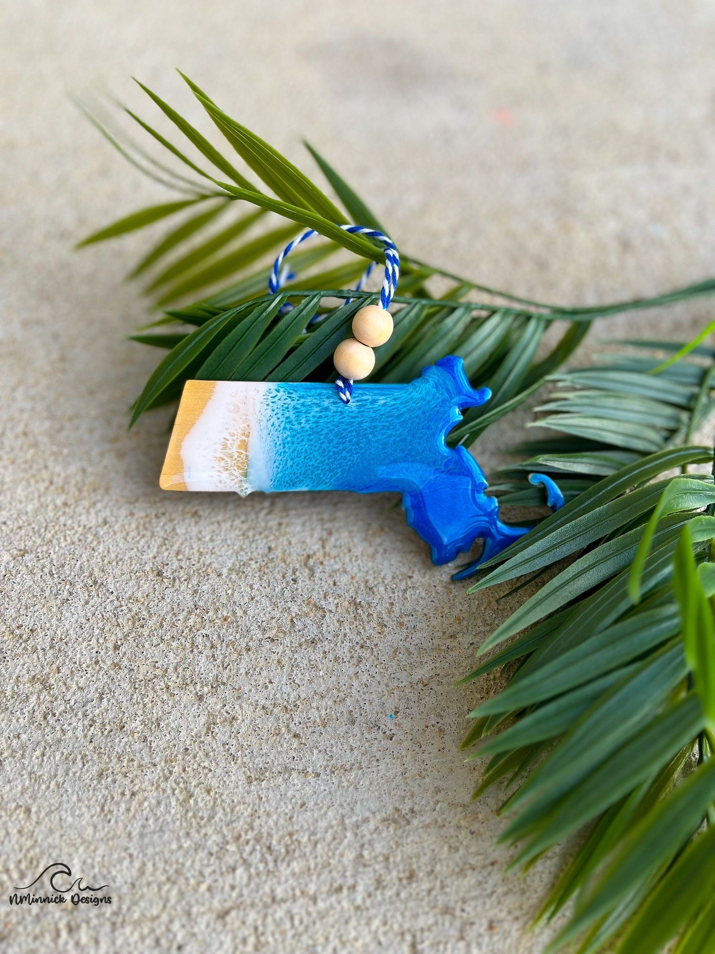Handmade Massachusetts shaped wooden ornament featuring ocean resin waves, finished with blue and white twine and two natural wooden beads