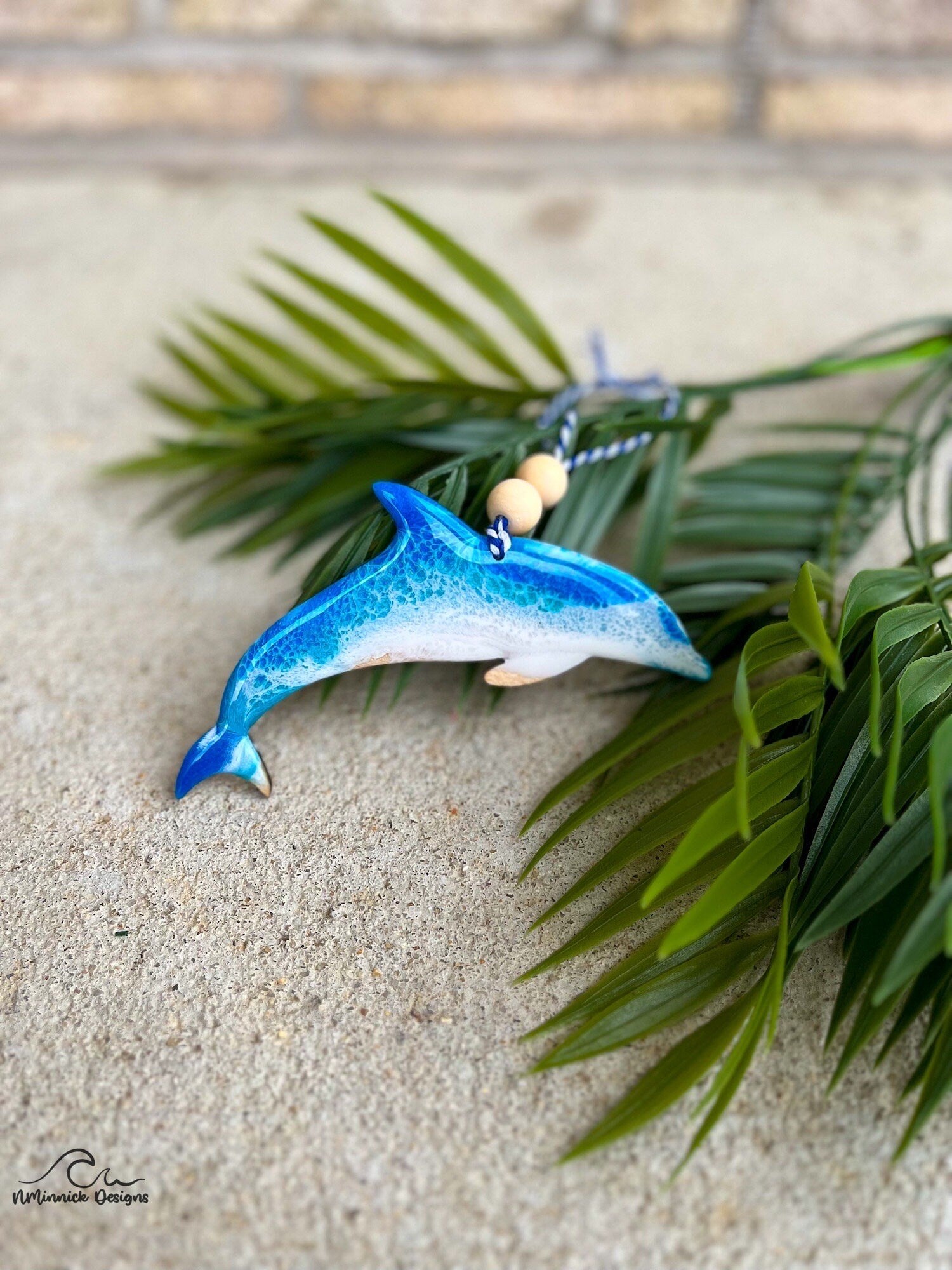 Handmade Dolphin shaped wooden ornament featuring ocean resin waves, finished with blue and white twine and two natural wooden beads