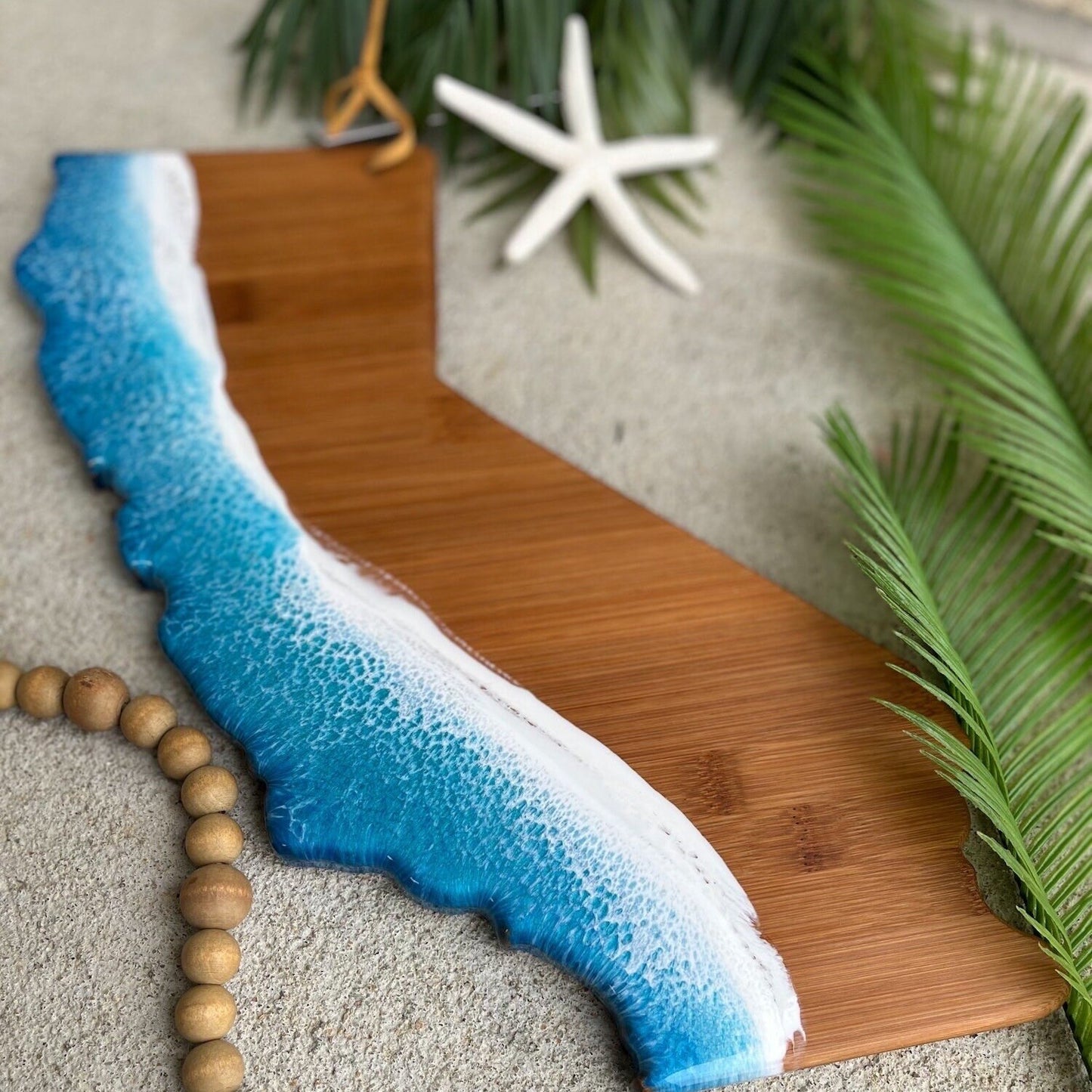 sustainable bamboo cutting board shaped like the state of California with the coastline covered in epoxy resin ocean wave art
