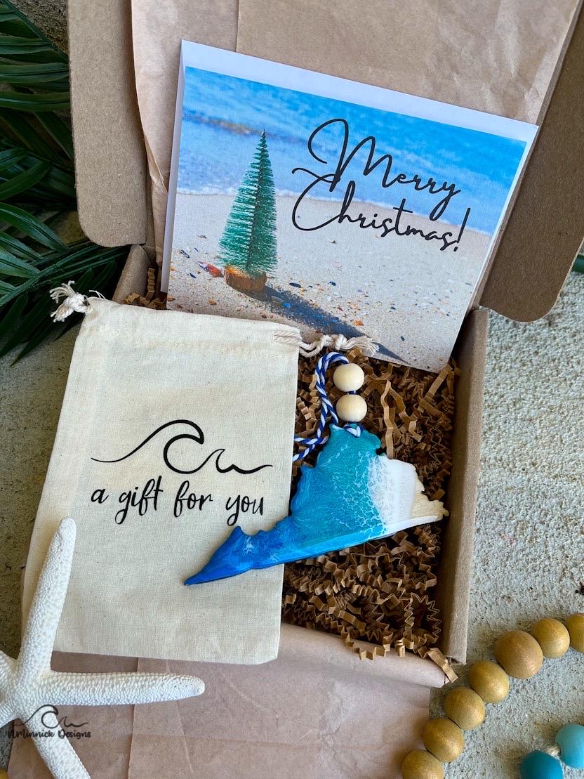 A Virginia shaped wooden christmas ornament with ocean resin art, resembling the waves of the ocean. In a box with an ornament keepsake bag with a wave that says "a gift for you" and a Merry Christmas custom card.