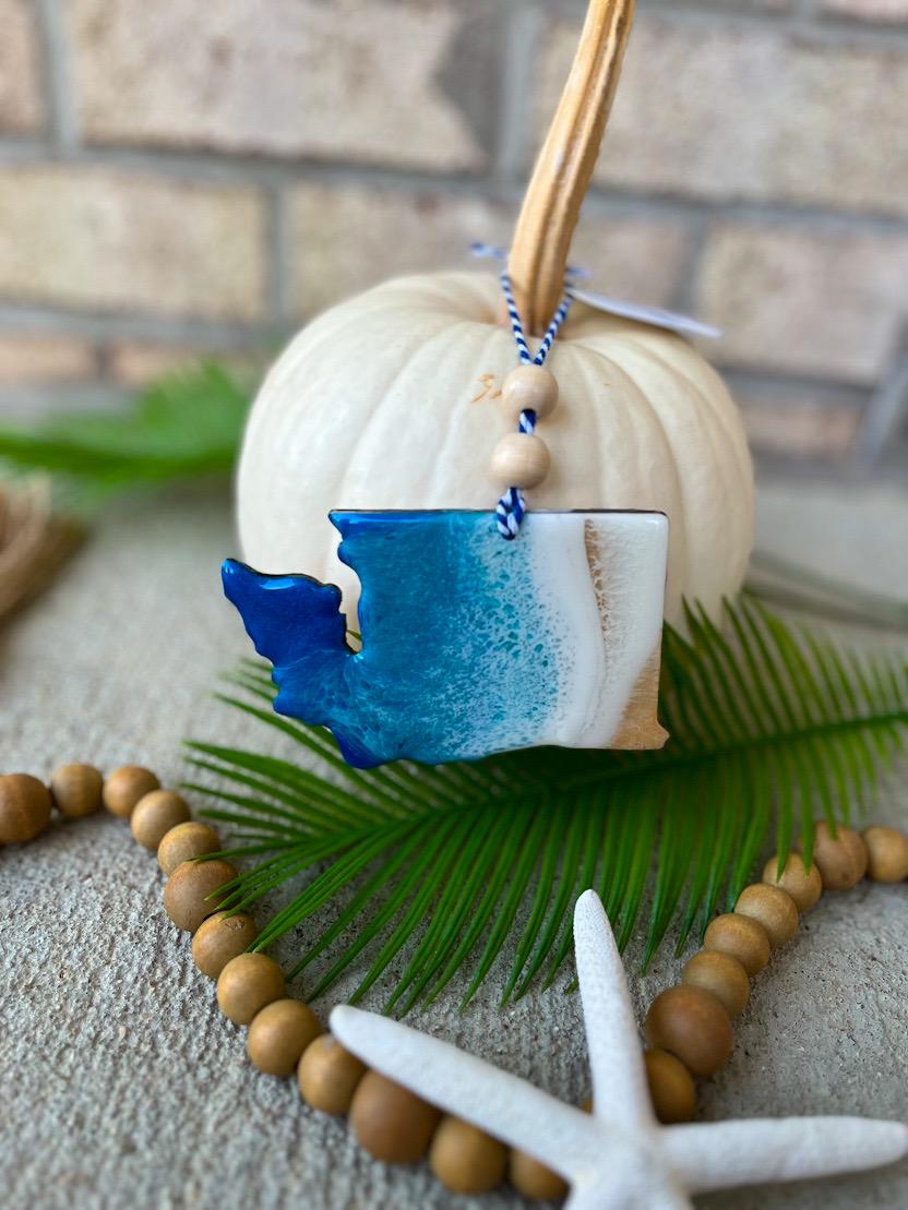 Handmade Washington state ocean resin ornament displayed on a white pumpkin, coastal fall decor with ocean wave design