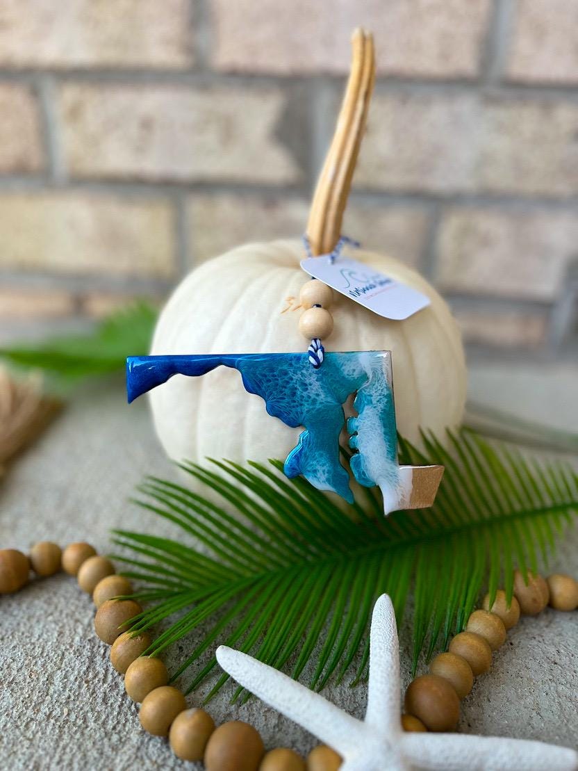 Handmade Maryland state ocean resin ornament displayed on a white pumpkin, coastal fall decor featuring ocean wave design