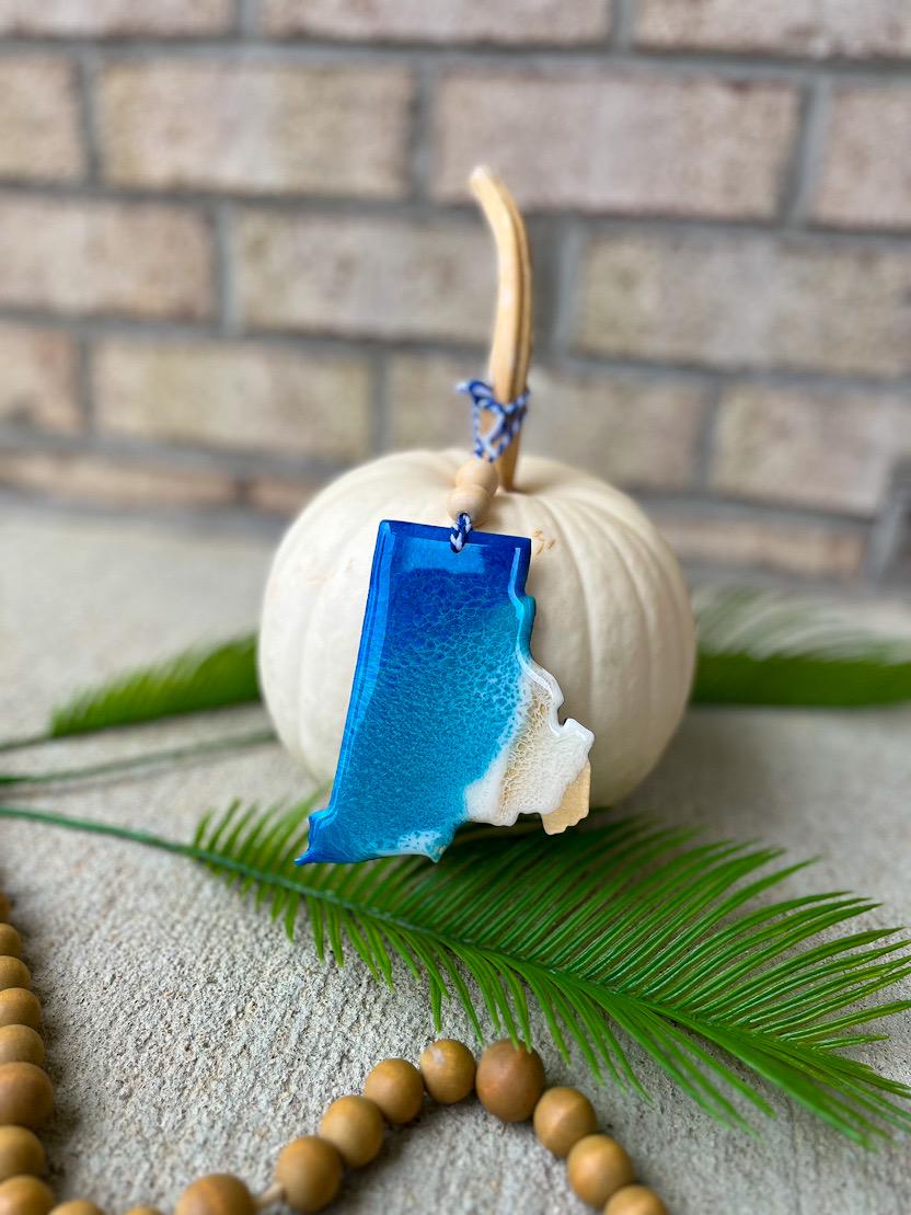 Handmade Rhode Island ocean resin ornament resting on a white pumpkin, coastal design featuring ocean wave details
