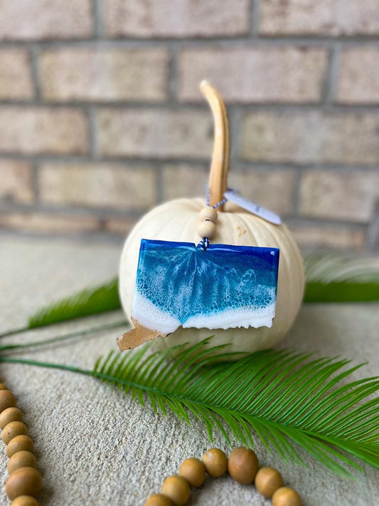 Handmade Connecticut ocean resin ornament resting on a white pumpkin, coastal design inspired by Connecticut beaches and ocean waves