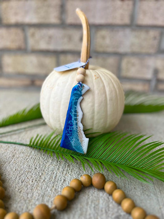 Handmade Delaware ocean resin ornament resting on a white pumpkin, coastal design inspired by Delaware beaches and ocean waves