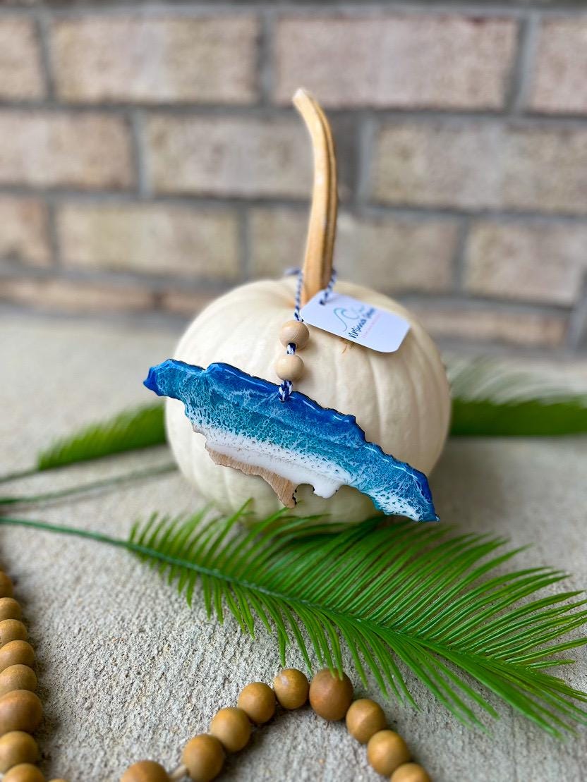 Handmade Jamaica ocean resin ornament resting on a white pumpkin, tropical beach-inspired design with ocean wave details