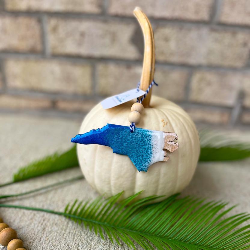 Handmade North Carolina ocean resin ornament resting on a white pumpkin, Outer Banks coastal decor with ocean wave details