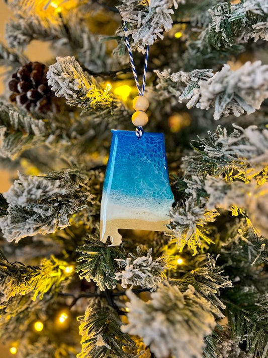 Handmade Alabama shaped wooden ornament featuring ocean resin waves, finished with blue and white twine and two natural wooden beads