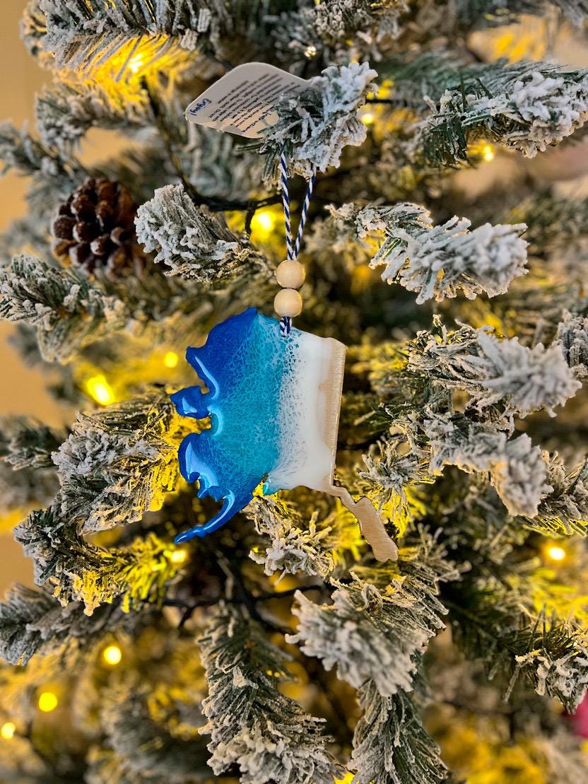 Handmade Alaska shaped wooden ornament featuring ocean resin waves, finished with blue and white twine and two natural wooden beads