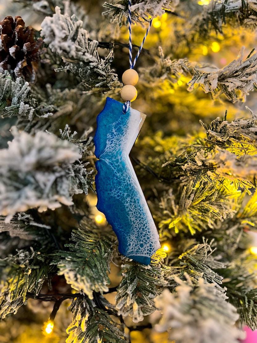 Handmade California shaped wooden ornament featuring ocean resin waves, finished with blue and white twine and two natural wooden beads
