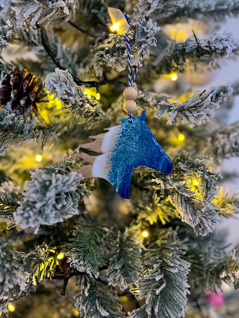 Handmade Wild Horse shaped wooden ornament featuring ocean resin waves, finished with blue and white twine and two natural wooden beads. Optional engraving on the back: Corolla.
