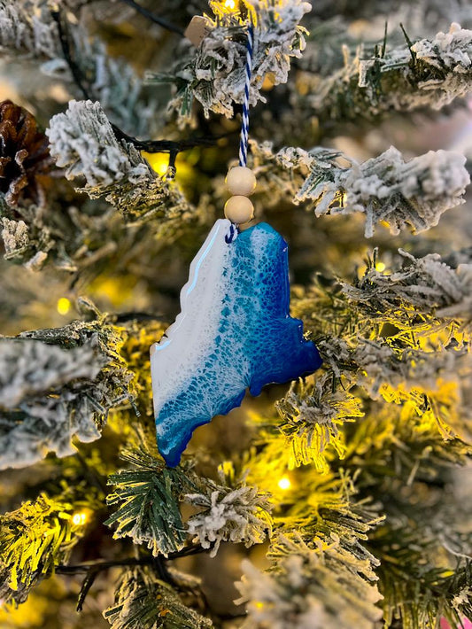 Handmade Maine shaped wooden ornament featuring ocean resin waves, finished with blue and white twine and two natural wooden beads