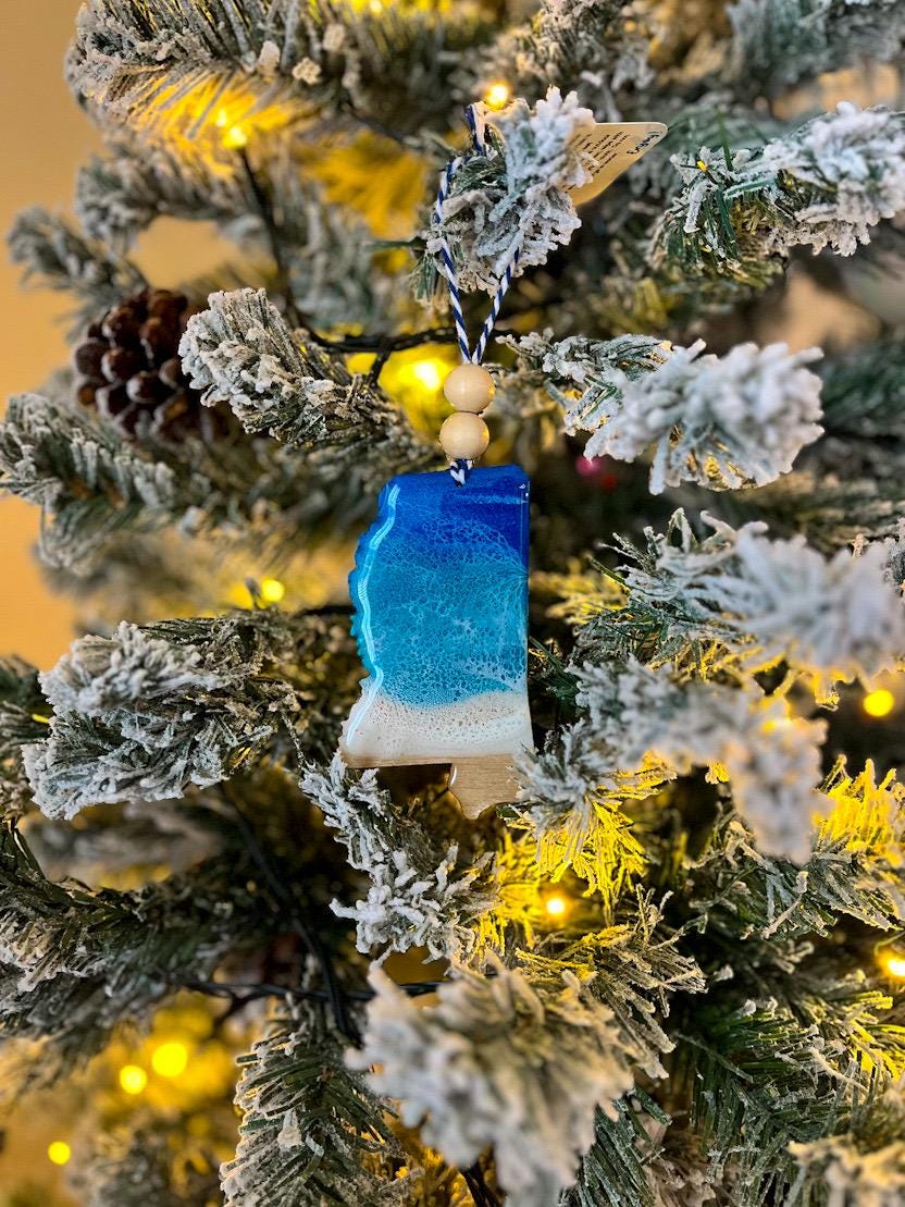 Handmade Mississippi shaped wooden ornament featuring ocean resin waves, finished with blue and white twine and two natural wooden beads