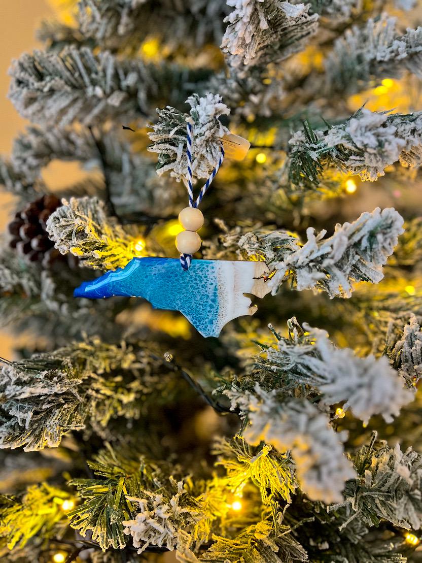 Handmade North Carolina shaped wooden ornament featuring ocean resin waves, finished with blue and white twine and two natural wooden beads