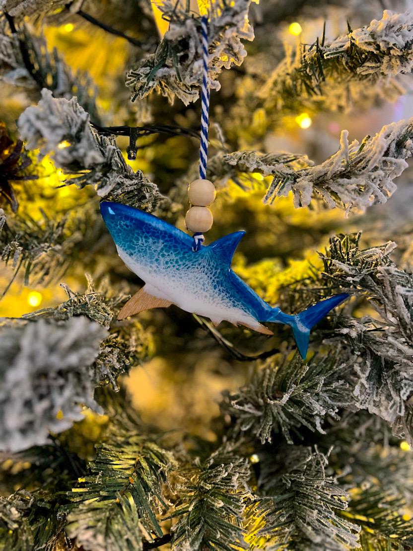 Handmade Shark shaped wooden ornament featuring ocean resin waves, finished with blue and white twine and two natural wooden beads. Choose from Great White, Hammerhead, or Galapagos.