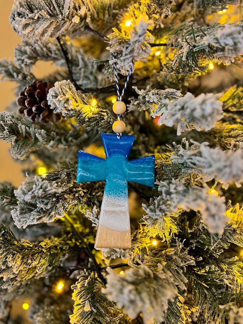 Handmade Cross shaped wooden ornament featuring ocean resin waves, finished with blue and white twine and two natural wooden beads