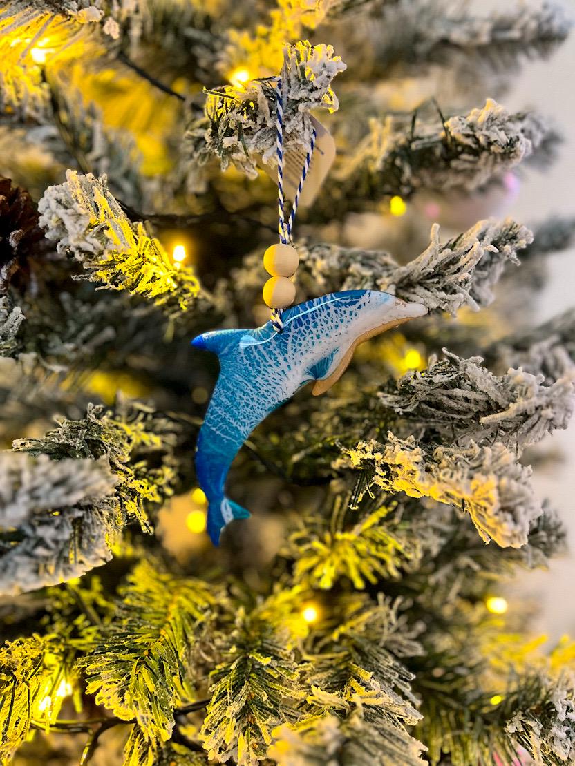 Handmade dolphin shaped wooden ornament featuring ocean resin waves, finished with blue and white twine and two natural wooden beads