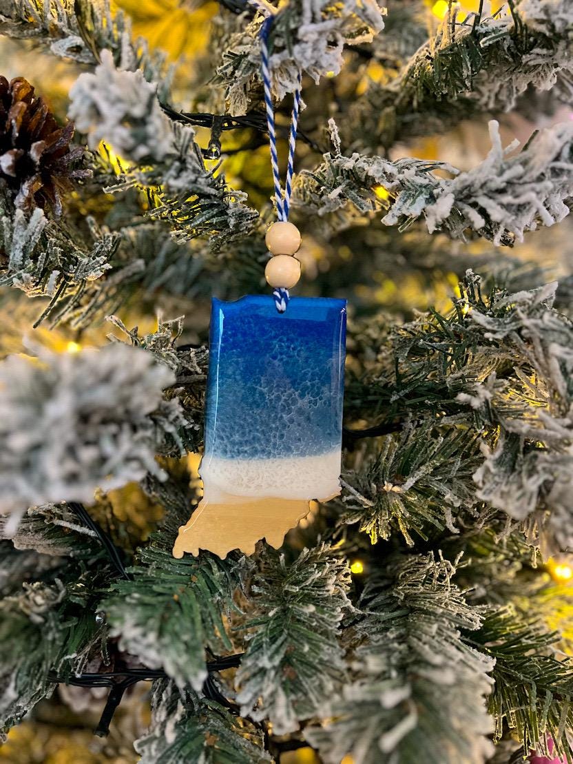Handmade Indiana shaped wooden ornament featuring resin waves, finished with blue and white twine and two natural wooden beads