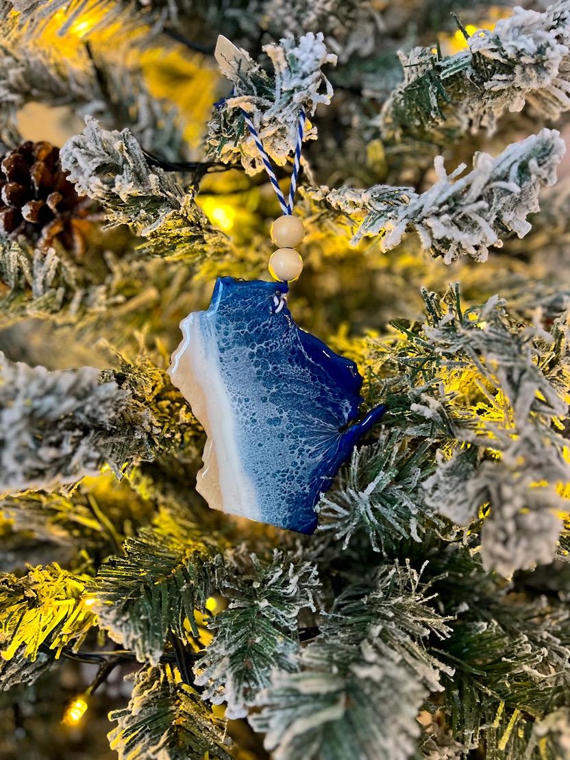 Handmade Wisconsin shaped wooden ornament featuring resin waves, finished with blue and white twine and two natural wooden beads