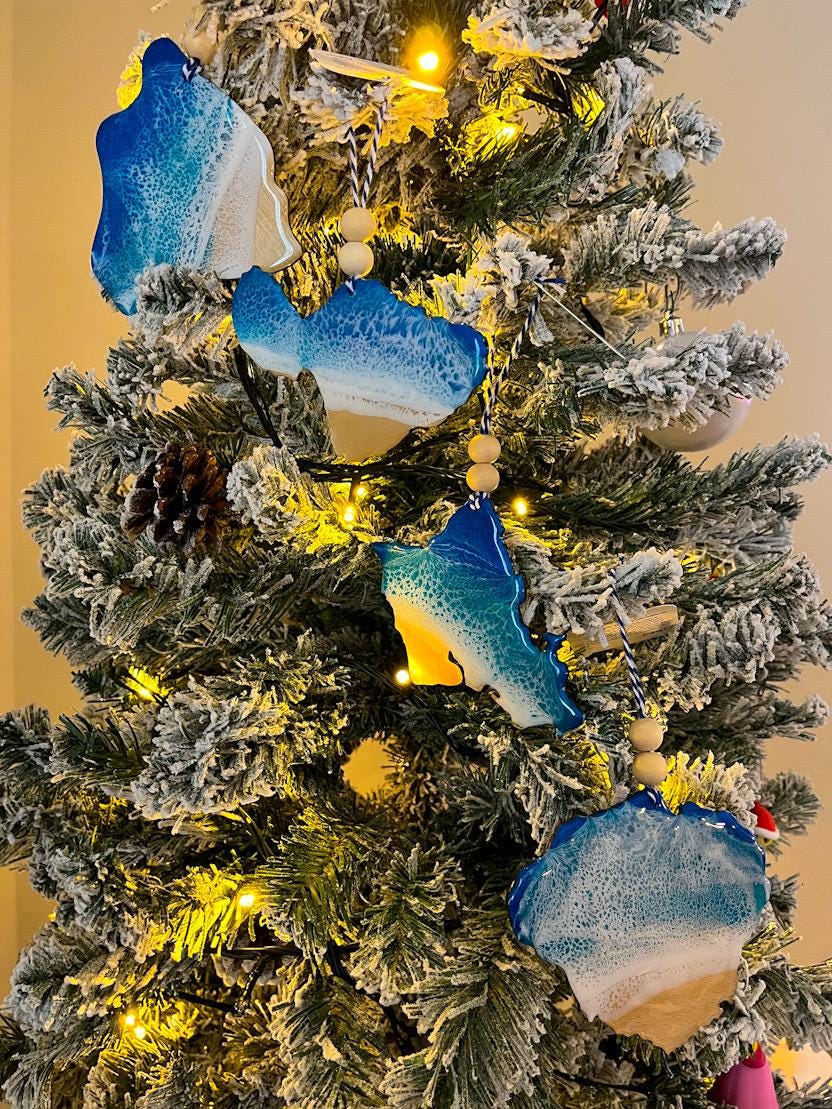 Handmade Hawaiian Island shaped wooden ornaments featuring ocean resin waves, each finished with blue and white twine and two natural wooden beads. Choose from Hawaii, Maui, Oahu, or Kauai.