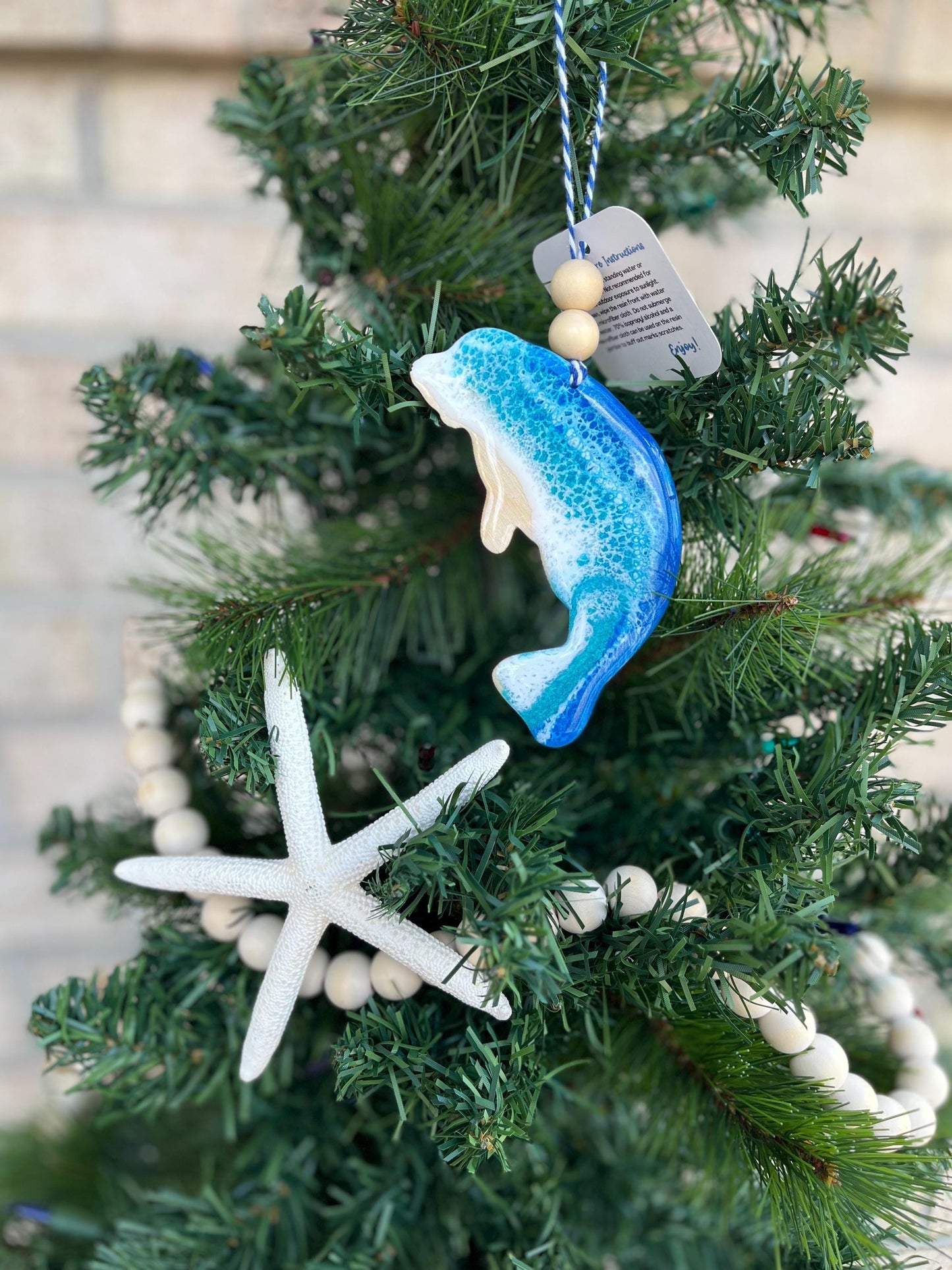 Manatee ornament with ocean resin waves and finished with two wooden beads and blue and white twine