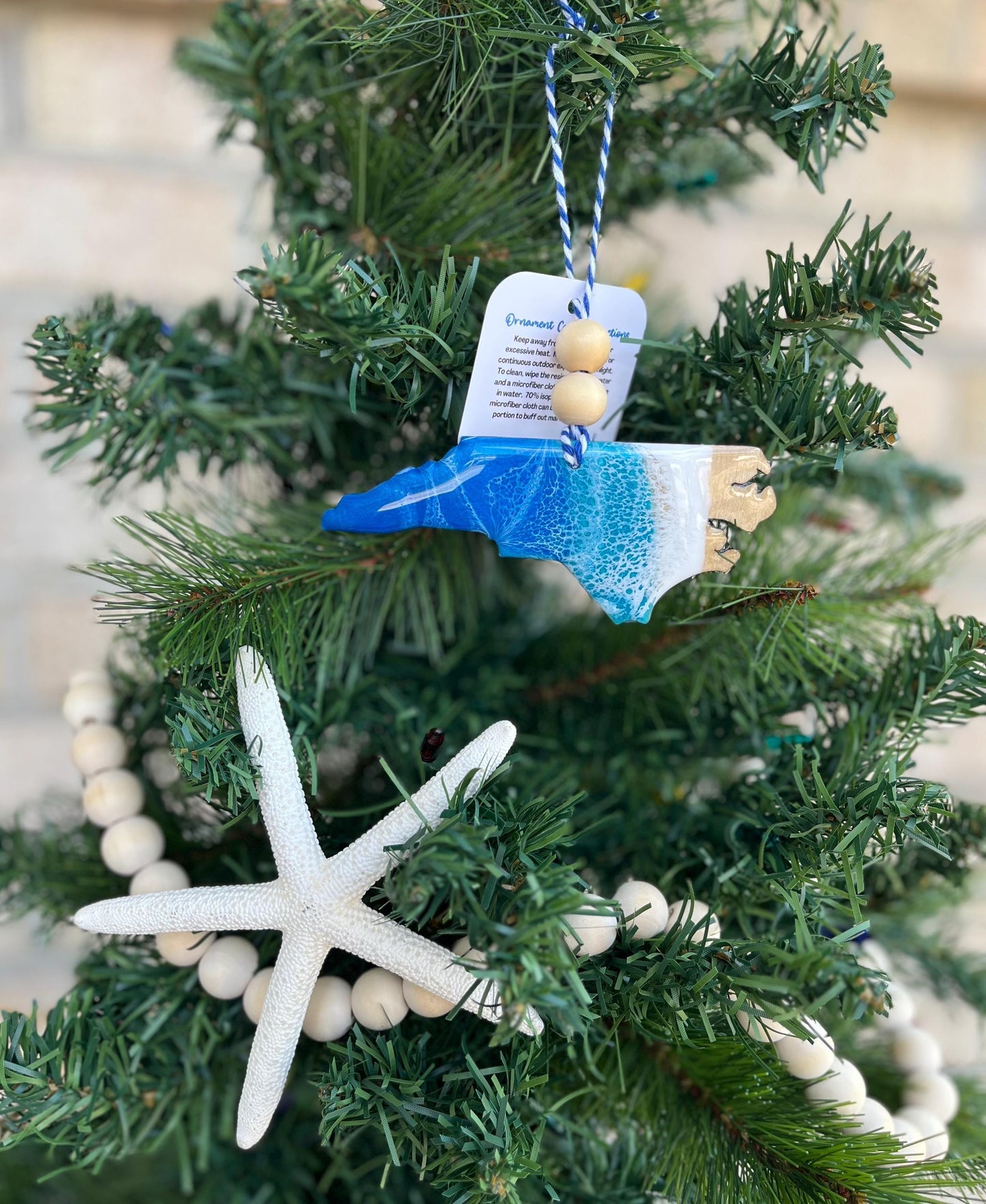 North Carolina ornament with ocean resin waves and finished with two wooden beads and blue and white twine