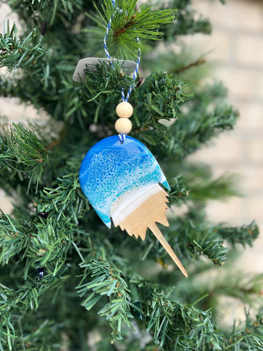 Horseshoe Crab ornament with ocean resin art and finished with two wooden beads and blue and white twine. Hanging on a christmas tree.