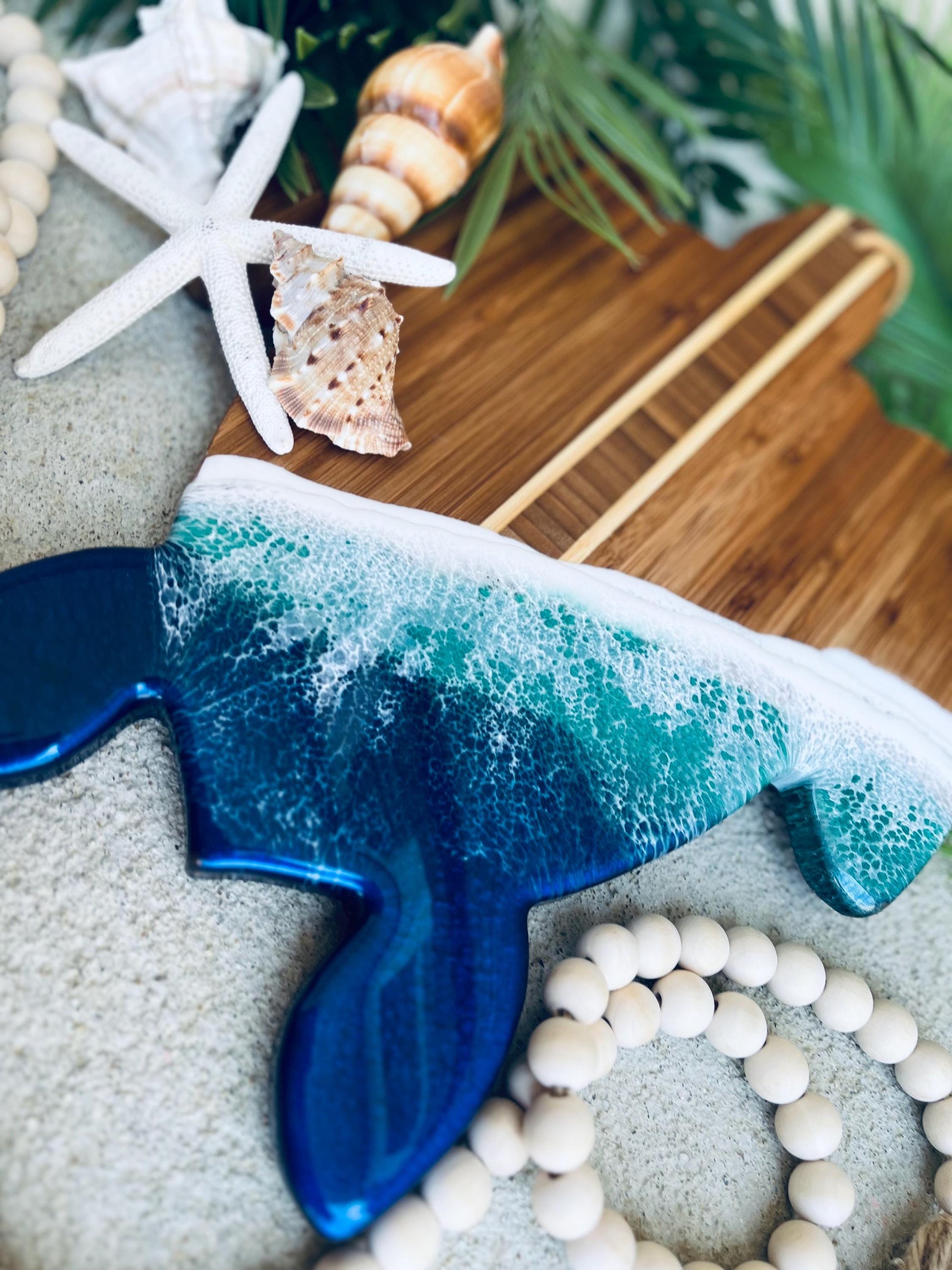 sea turtle shaped bamboo charcuterie board with blue and teal ocean resin waves on the bottom.