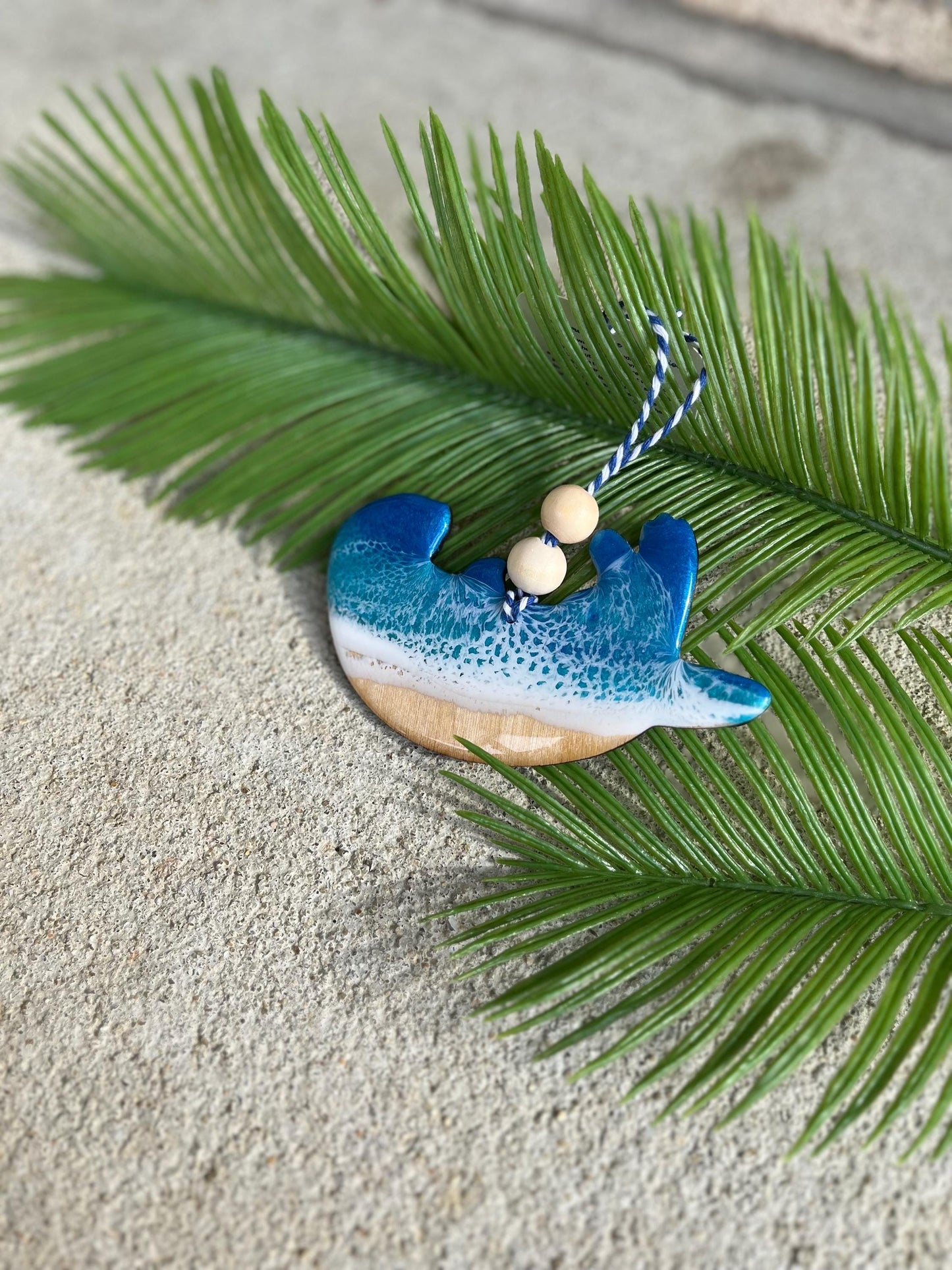 Sea Otter Ornament laying against palm leaves