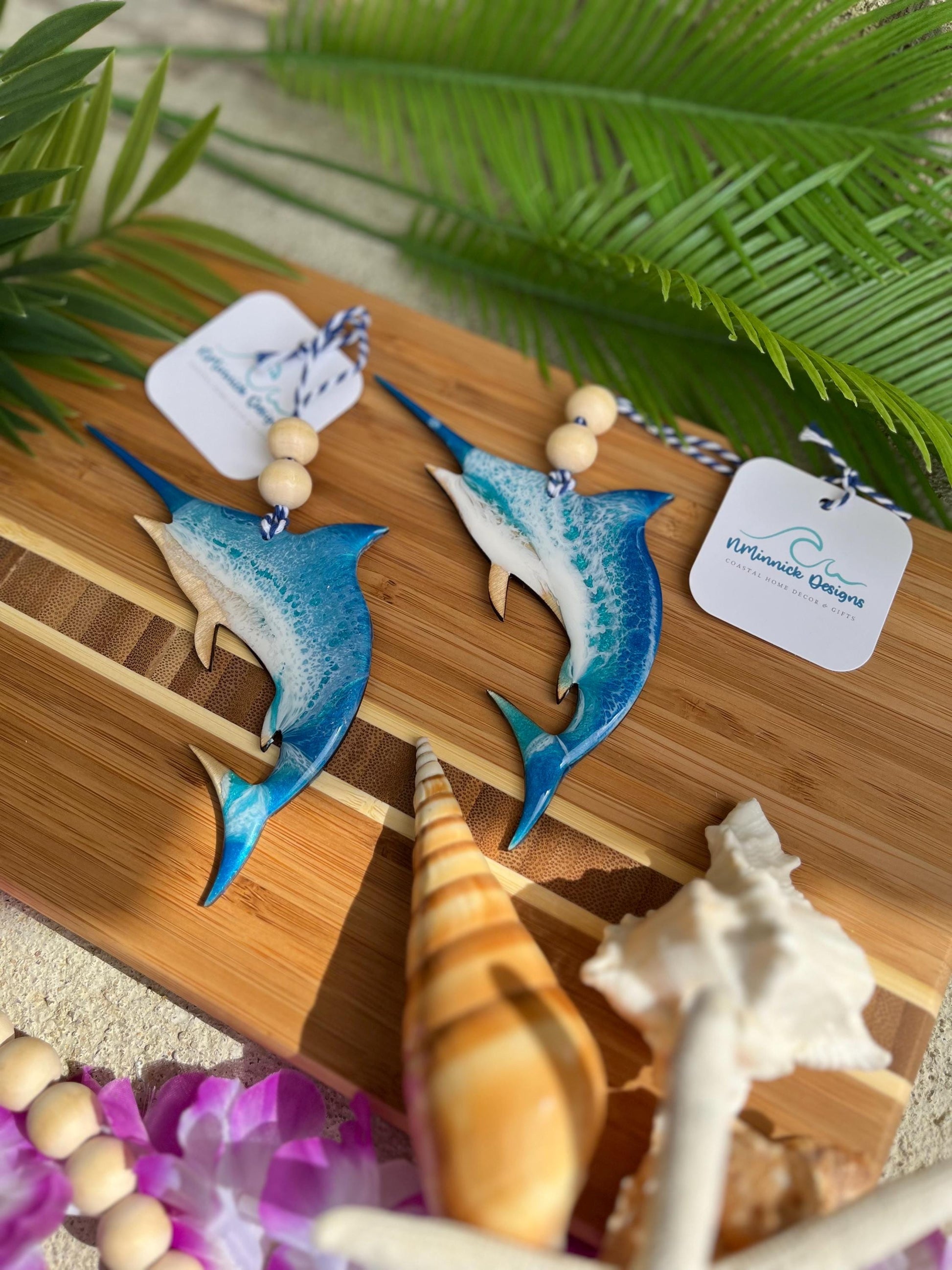 Marlin Ocean Ornament laying on a bamboo board among seashells and palm leaves