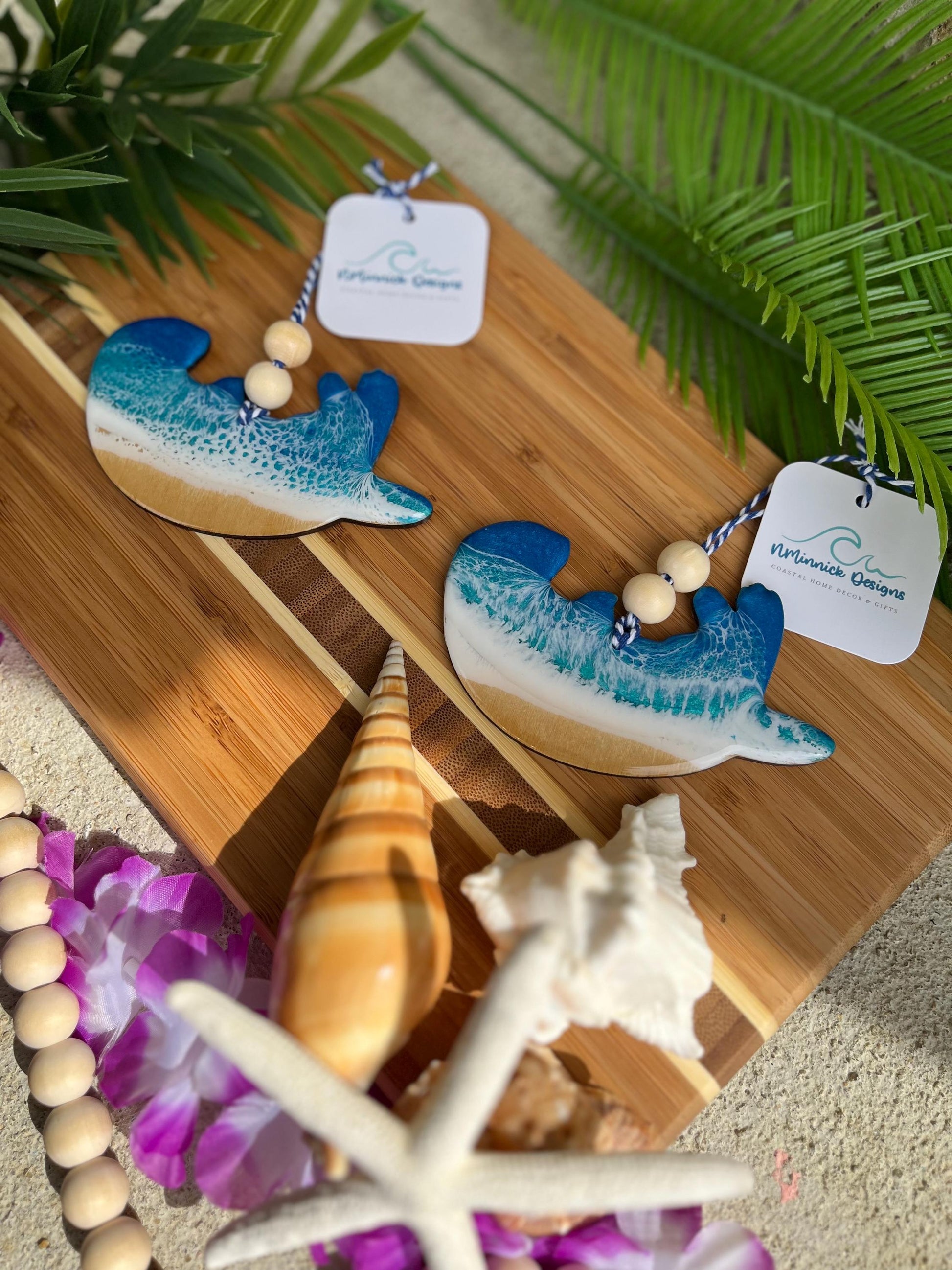 Sea Otter Ornament laying on a bamboo board among seashells and palm leaves