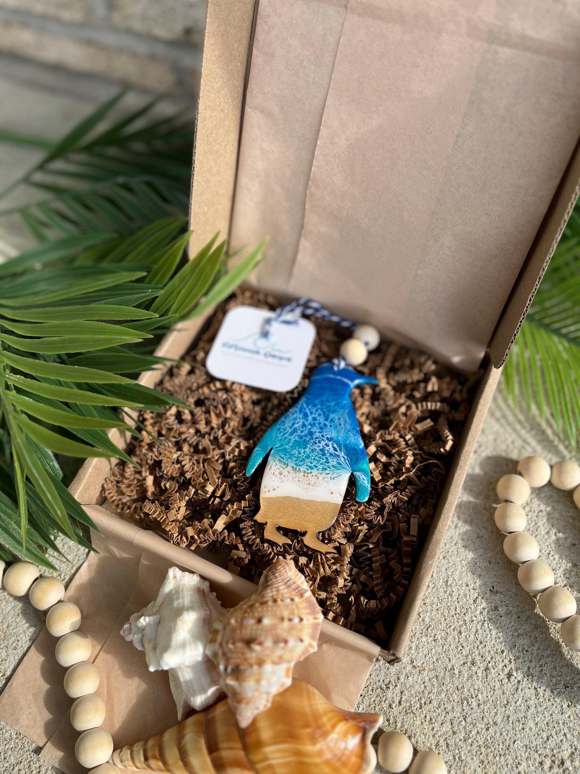 Penguin Ocean Resin Ornament laying in an ecofriendly gift box
