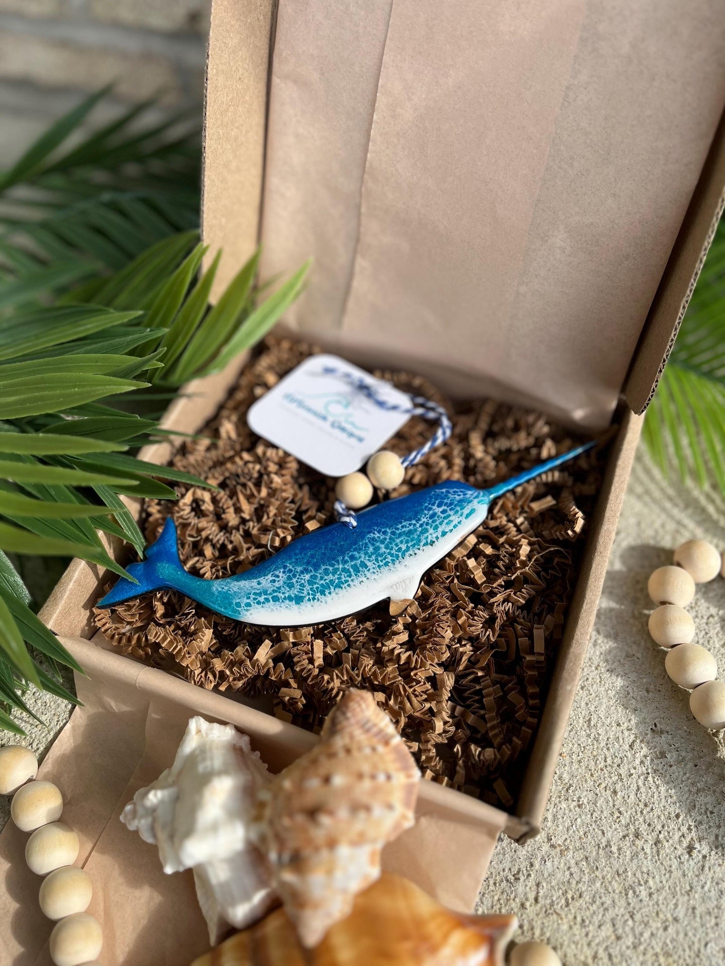 Narwhal Ornament laying in an ecofriendly gift box